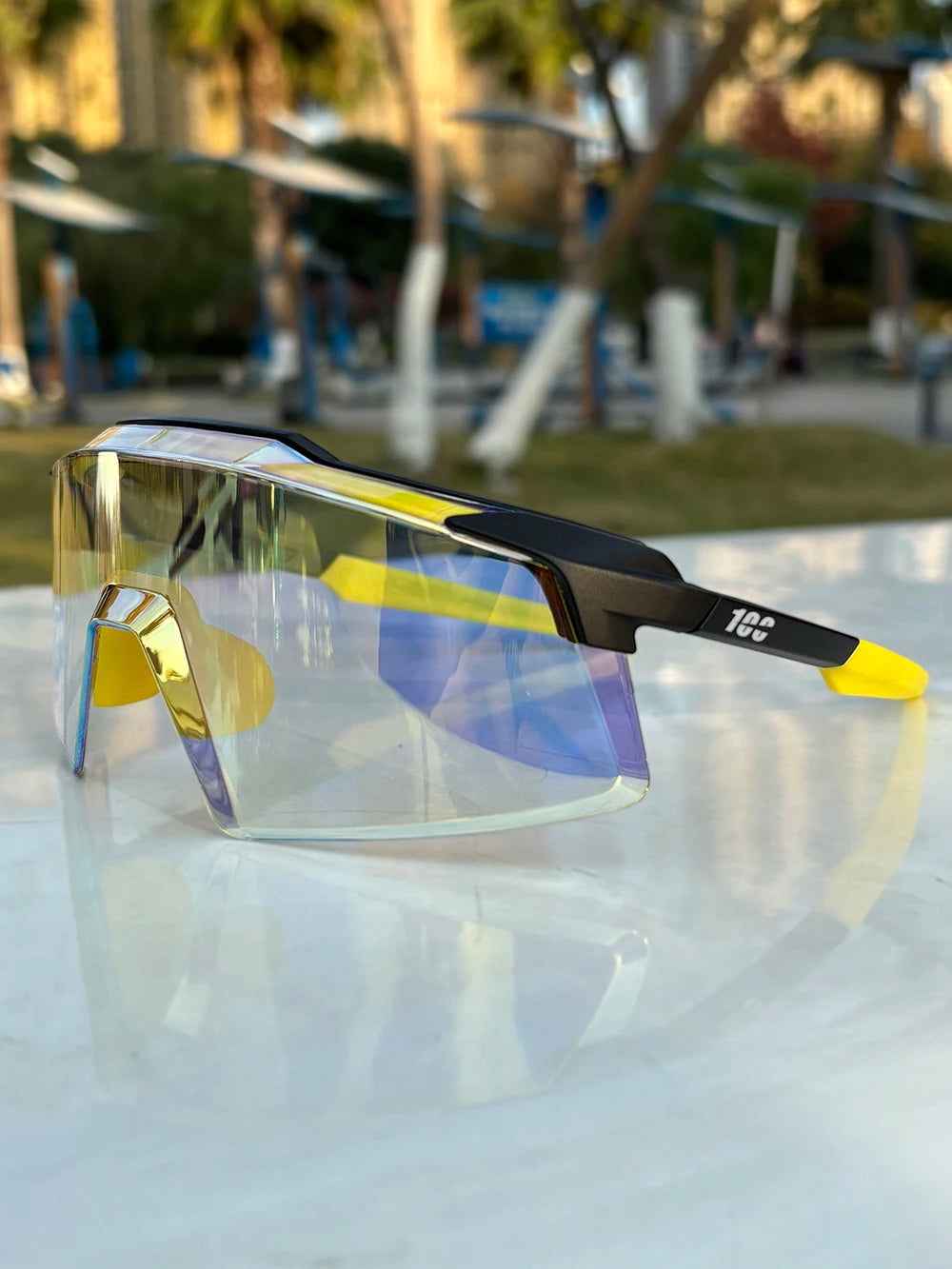 Trendy oversized sport sunglasses with yellow accents and mirrored lenses on outdoor table