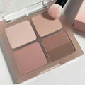 Neutral eyeshadow palette with four nude shades and makeup brush on white background