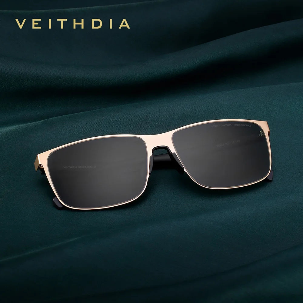 Gold frame square sunglasses with black lenses on green fabric background