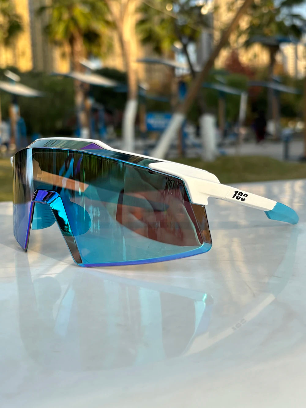 Blue mirrored sports sunglasses with white frame on outdoor table