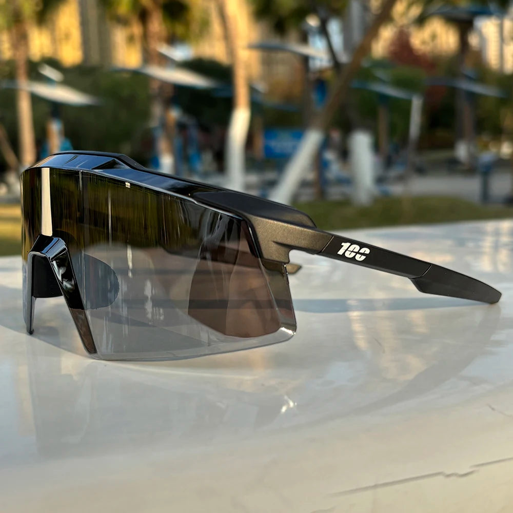 Black sports sunglasses with large reflective lenses displayed outdoors on a white surface.