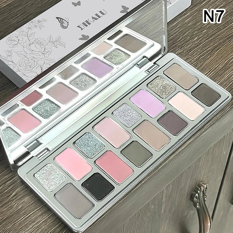 Metallic and matte eyeshadow palette with pink, purple, gray, and nude shades on a wooden table