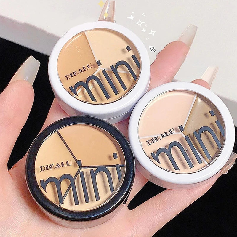 Hand holding three DIKALU mini cream concealer palettes in neutral shades