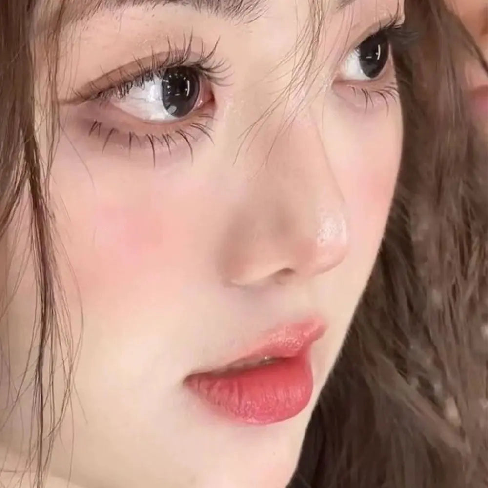 Close-up of woman with natural makeup, long lashes, soft pink blush and glossy lips