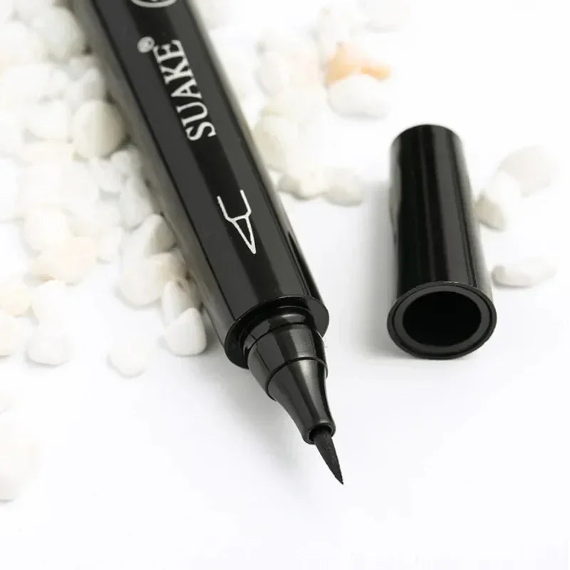 Black liquid eyeliner pen with cap off on white background and decorative stones