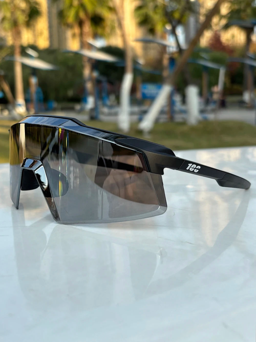 Black sports sunglasses with large tinted shield lens on outdoor table