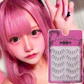 Woman with pink hair and dramatic eye makeup holding a pack of false eyelashes