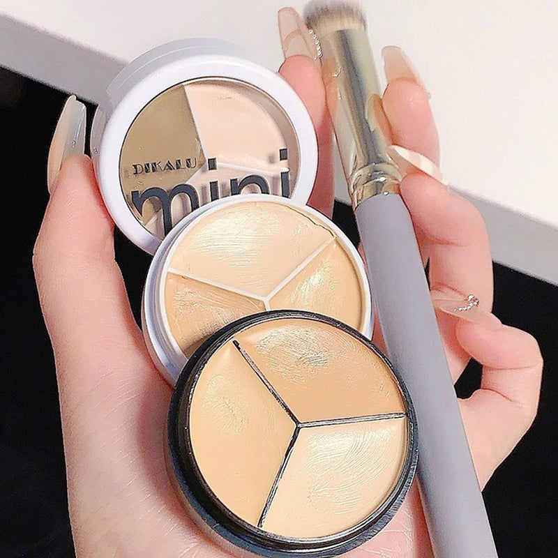 Hand holding cream concealer palette and makeup brush, beige shades for face makeup