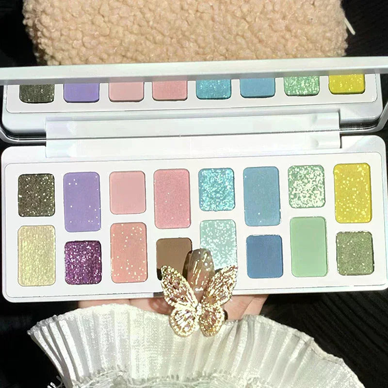 Colorful eyeshadow palette with shimmer and matte pastel shades, held by hand with butterfly ring