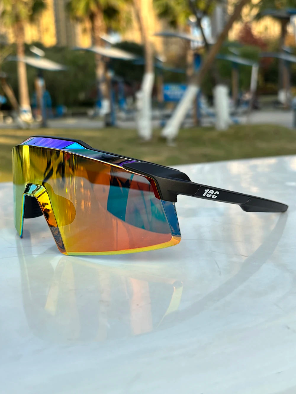 Sporty mirrored sunglasses with black frame and rainbow lens on outdoor table