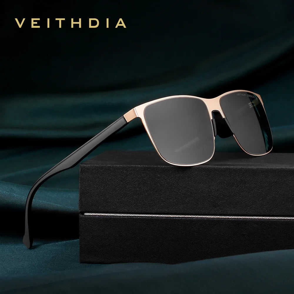 Modern square sunglasses with gold frame and dark lenses on black display box