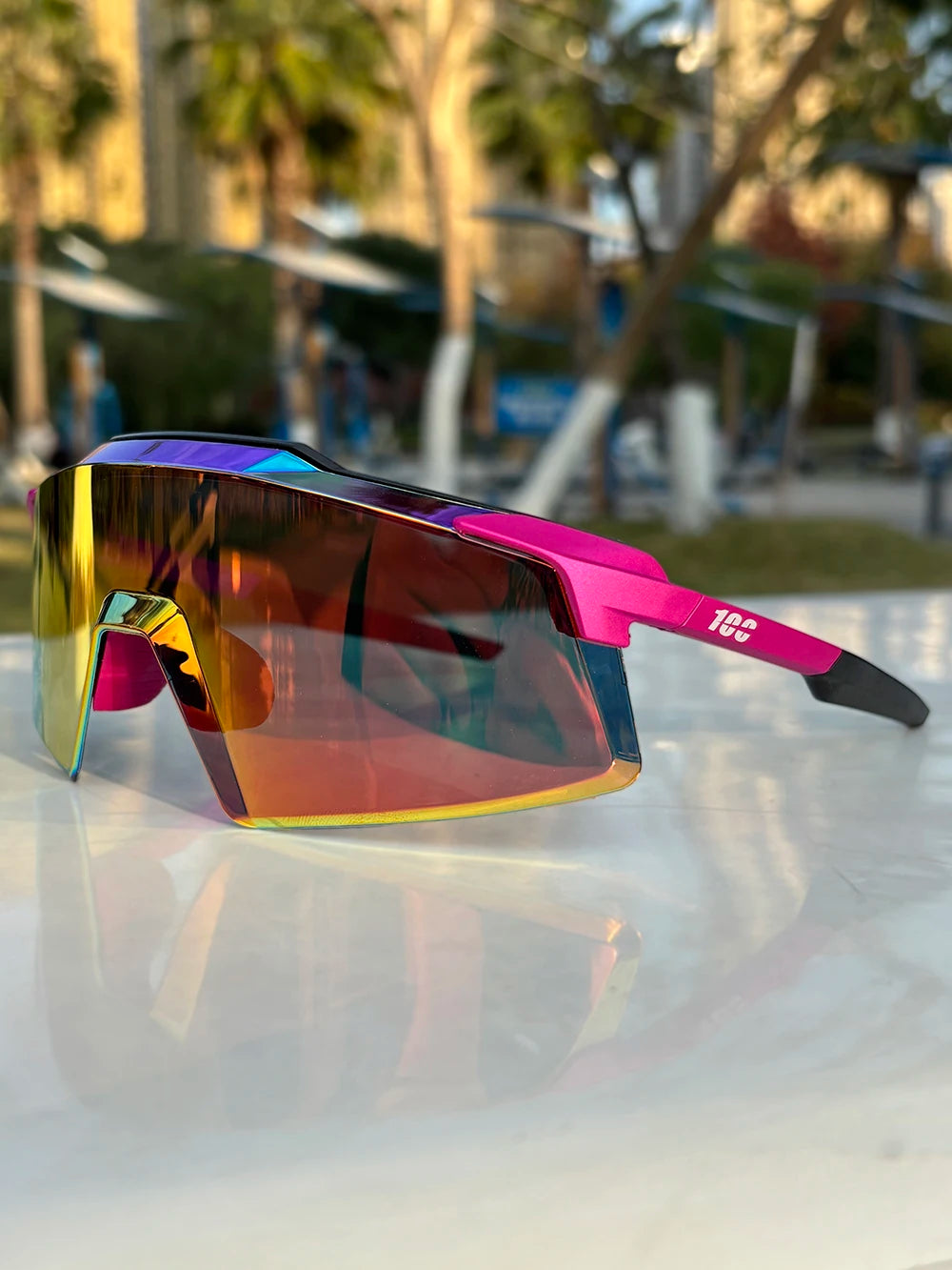 Colorful mirrored sports sunglasses with pink and yellow frame on outdoor table