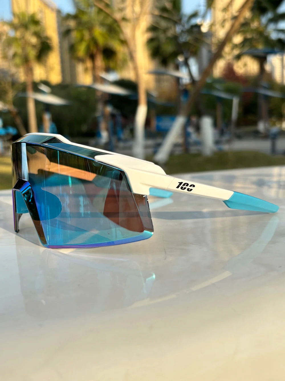 White and blue mirrored sport sunglasses with angular shield lens on outdoor table
