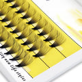Pack of black individual false eyelash extensions on a yellow tray, beauty accessory