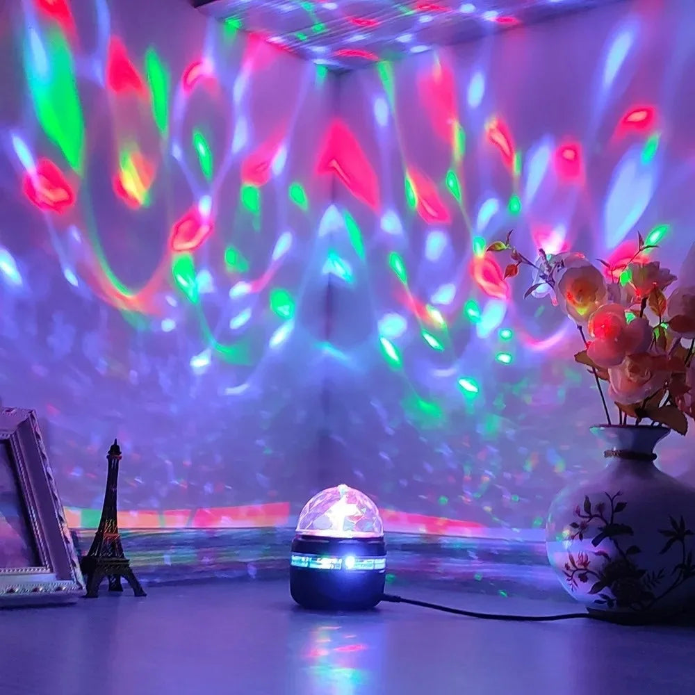 Colorful LED projector night light casting red, green, and blue patterns on wall, with vase and decor