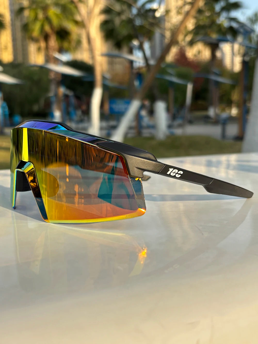 Sporty oversized sunglasses with orange mirrored lens and black frame, outdoor setting