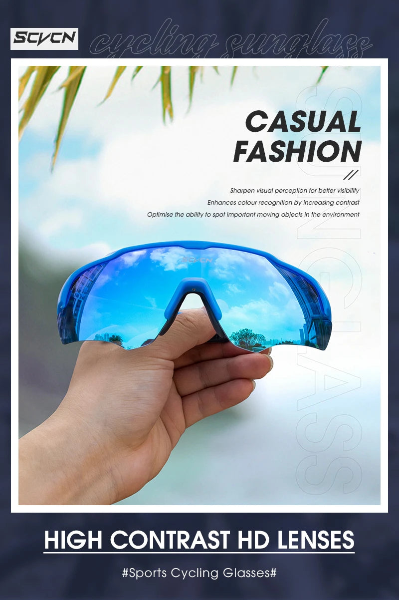 Hand holding blue high contrast sports cycling sunglasses outdoors with sky reflection.