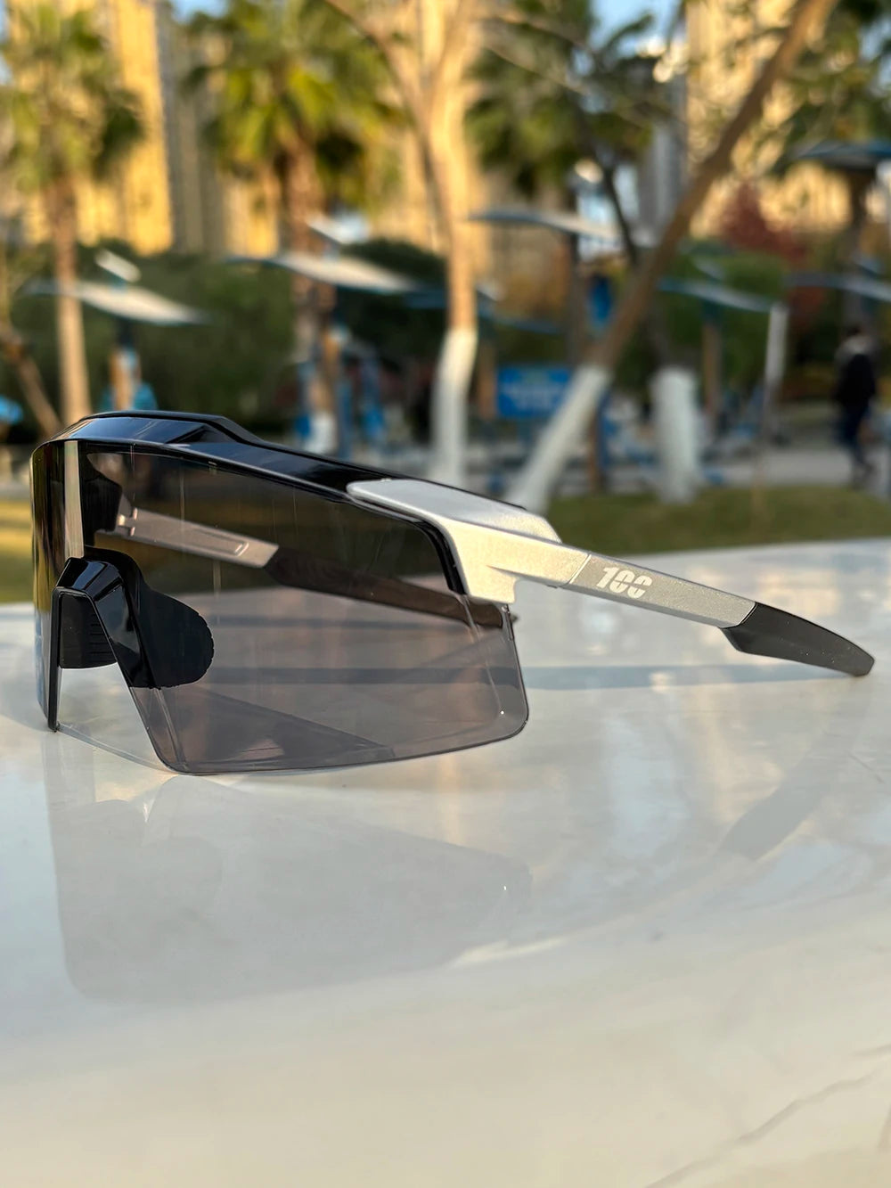 Modern black and silver sports sunglasses with dark lenses outdoors on a sunny day